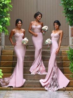 three bridesmaids in pink dresses standing on steps with bouquets and greenery