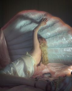 a woman laying on top of a bed next to a lamp and pillow covered in plastic