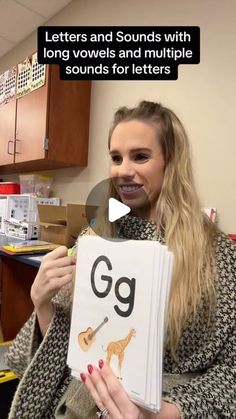 a woman holding up a book with the letter g on it and an image of a giraffe