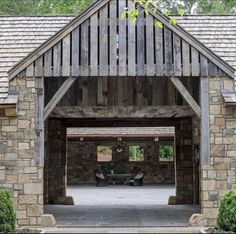 an open garage with stone walls and wooden roof