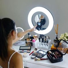 a woman is looking at her make up in front of the mirror and holding out her hand