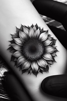 a black and white photo of a sunflower on the side of a woman's leg