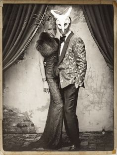 a man and woman dressed up in costume posing for a photo with an animal mask on