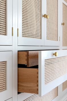 a white cabinet with wooden drawers and perforated doors