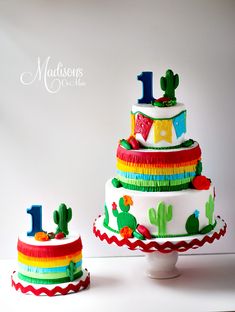 a three tiered cake decorated with colorful ribbons and cactus decorations is shown in front of a white background