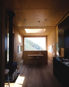 a room with wooden walls and flooring has a table in the middle, near a window