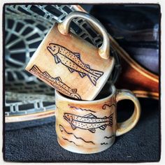 two coffee mugs with fish designs on them