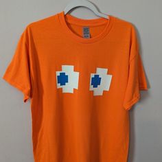 an orange t - shirt with two blue squares on the front and one white square on the back