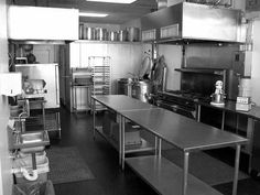 an industrial kitchen with stainless steel appliances and tables in front of the stove top oven