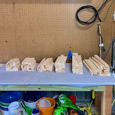 several wooden blocks sitting on top of a table next to cups and other items in front of a wall