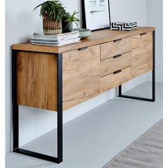 a wooden sideboard with black metal legs and a potted plant sitting on top