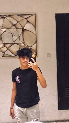 a young man taking a selfie in front of a mirror with his cell phone