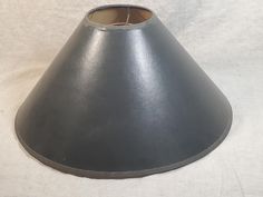 a gray lamp shade sitting on top of a white cloth covered tablecloth with a small hole in the middle