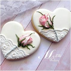 two decorated heart shaped cookies with pink roses on them, one is cut in half