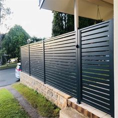 a car parked in front of a house with a black fence on the side of it