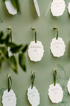 several tags are attached to the wall with green leaves on them and hanging from hooks