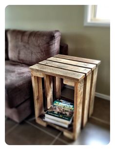 a small wooden table sitting next to a brown couch in a living room with a book on it