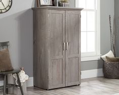 a tall wooden cabinet sitting in a living room next to a clock on the wall