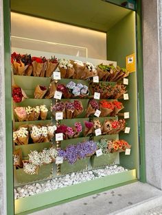 a flower shop window display filled with lots of flowers