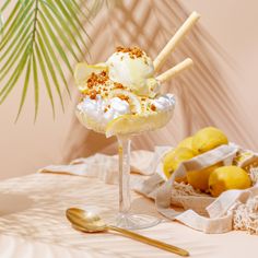 an ice cream sundae sits on a table next to lemons and a palm tree