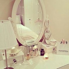 a mirror sitting on top of a white dresser next to a lamp and a bag