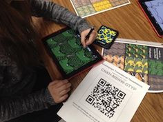 a person sitting at a table with some paper and cell phones on it, while another person holds up a qr - code