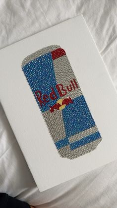 a red bull beer bottle is shown on a white paper with blue and silver beads