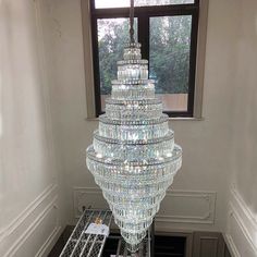 a very large crystal chandelier hanging from the ceiling in a room next to a window