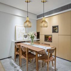 a dining room table surrounded by wooden chairs and pendant lights over it's head