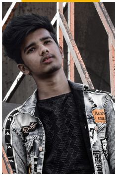 a young man with black hair wearing a denim jacket and looking up at the camera