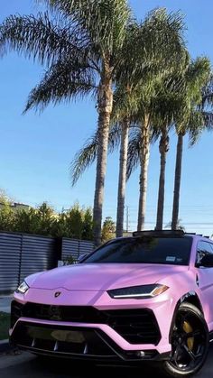 a pink lamb suv parked on the side of a road with palm trees in the background