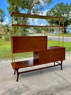 a wooden bed with two drawers and a shelf on the bottom, sitting in front of a tree