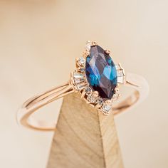 a blue diamond ring sitting on top of a wooden block