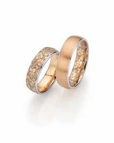 two gold and silver wedding rings with flowers on the inside, set against a white background