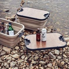 two coolers sitting on top of a rocky beach next to the ocean with beer bottles in them