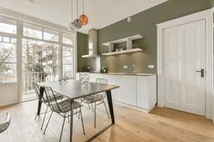 a dining room table and chairs in front of an open kitchen area with lots of windows