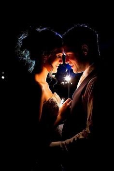 a man and woman standing next to each other in the dark with sparklers on their foreheads