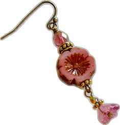 a pair of earrings with pink flowers and gold accents on them, hanging from a hook