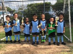 a group of young children standing next to each other holding trophy cups in their hands