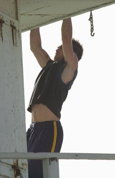 a man hanging off the side of a building while holding onto a metal object with one hand