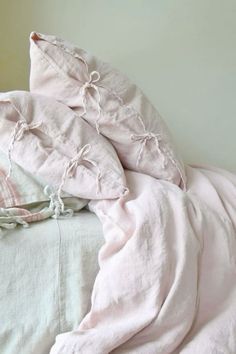 an unmade bed with pink sheets and pillows