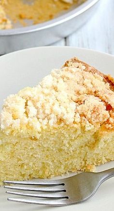 a piece of cake on a white plate with a fork next to it and another pie in the background