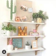 two white shelves with plants and pictures on them, one has a letter m in the middle