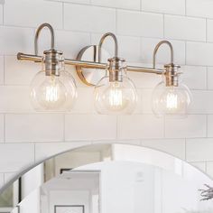 three light bathroom fixture with clear glass globes on the wall and mirror in front of it