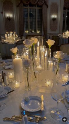 the table is set with white roses and candles for an elegant wedding reception or special event