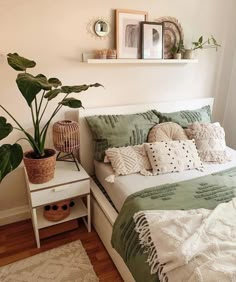 a bed with green and white sheets in a bedroom next to a potted plant