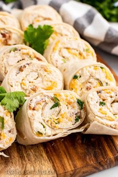 several burritos on a cutting board with cilantro