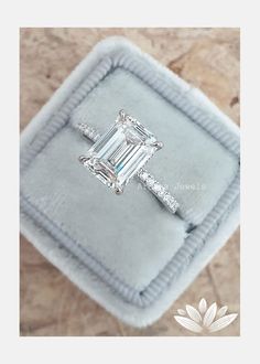 an emerald - cut diamond ring sits in a velvet box