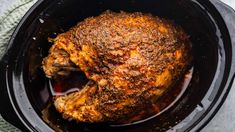 a cooked chicken in the crock pot with seasoning on it's side