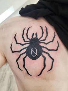 a black spider tattoo on the back of a man's upper arm and shoulder